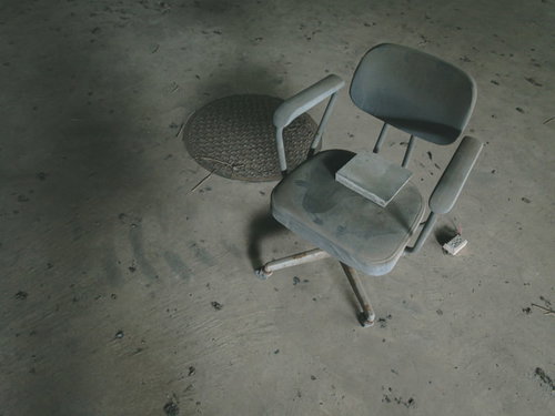 廃屋に残された灰色の椅子 コンクリート床に佇む古い家具