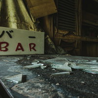荒廃したBARの看板とガラスの破片が散乱する室内の写真