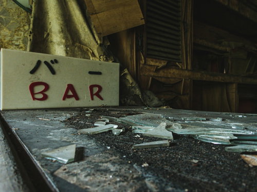 荒廃したBARの看板とガラスの破片が散乱する室内