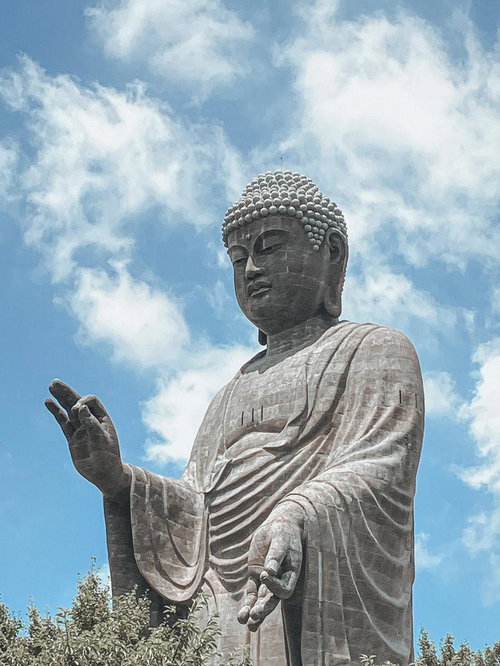 白い雲が流れる青空と石製の巨大な牛久大仏