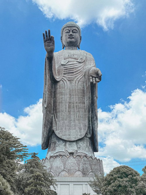 青空と雲を背景に聳える巨大な牛久大仏の立像