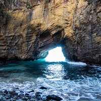 口を開ける龍宮窟、エメラルドグリーンの海が映える洞窟の写真