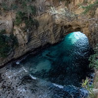 口を開ける海食洞・龍宮窟の波打ち際と洞窟内部の写真