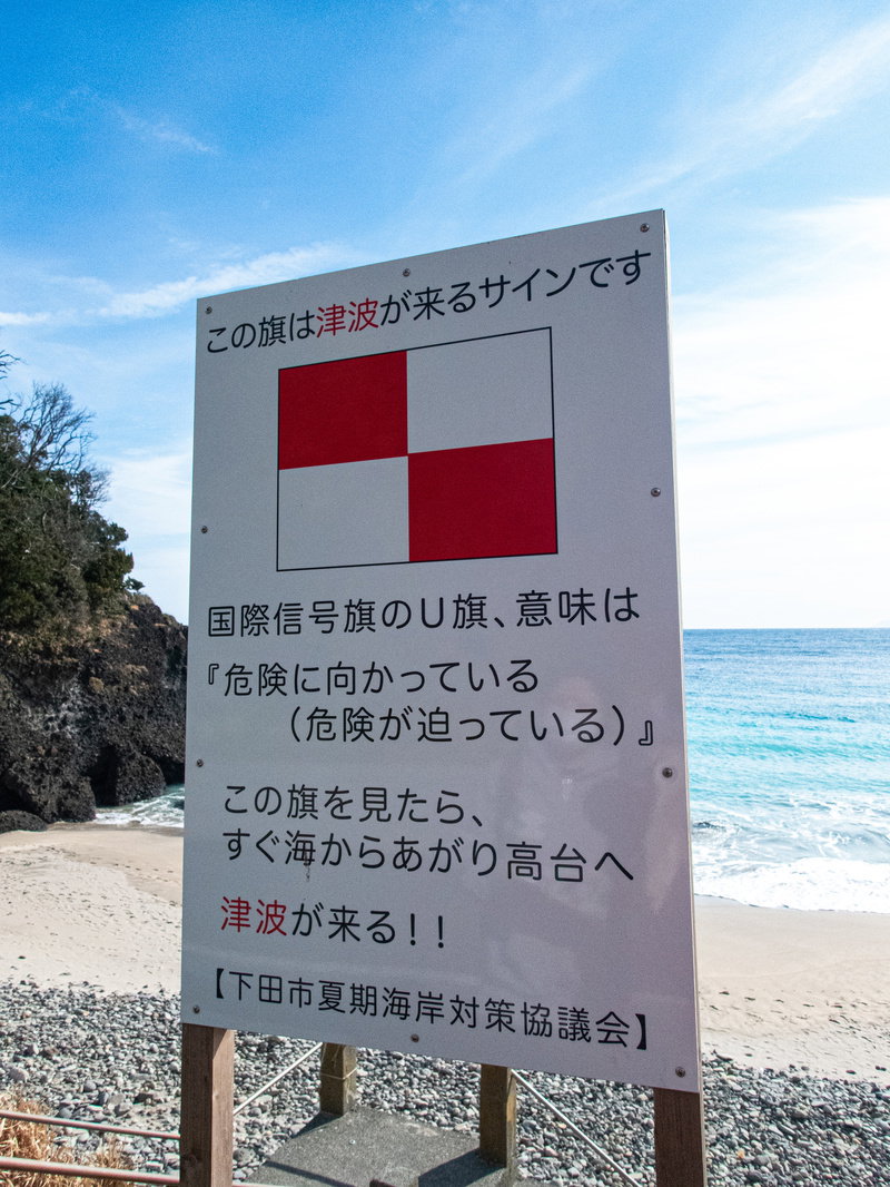 青い海と砂浜を背景にした白い津波警告看板