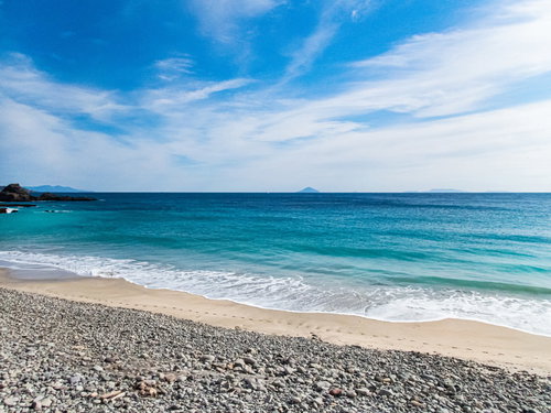 下田市の浜辺に打ち寄せる波と白い砂浜、龍宮窟の海岸風景