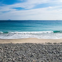 下田市の浜辺に並ぶ大粒の小石と龍宮窟の海岸風景の写真
