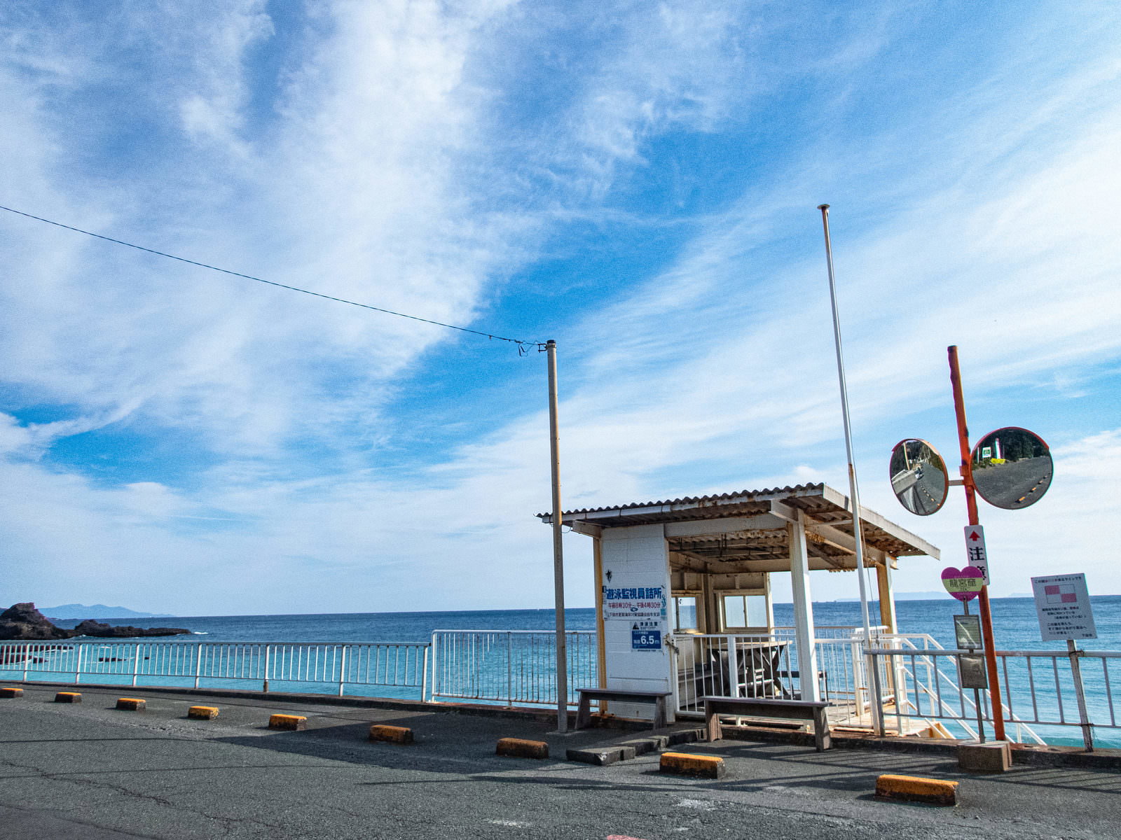 竜宮窟の海岸線に設置されたバス停と白い詰所、青空と水平線の風景