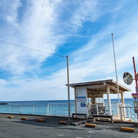 水平線と竜宮窟のバス停、白い詰所と海岸線の写真