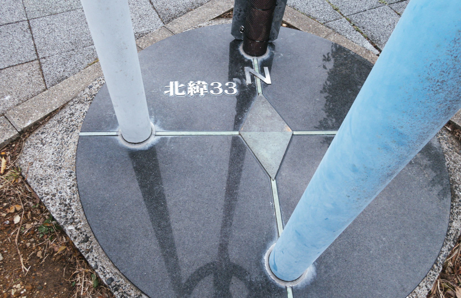 石畳の地面に北緯33度線展望台の表示と人の足元が写っている