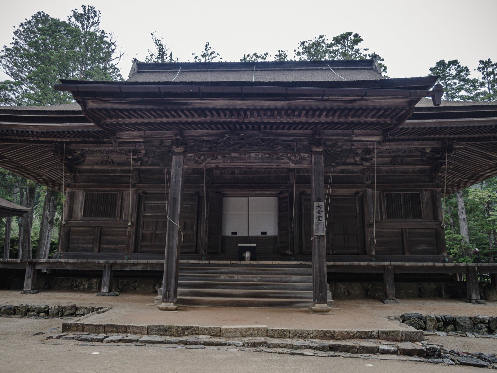 高野山の大会堂。黒い柱と装飾的な軒を持つ木造の大規模寺院建築