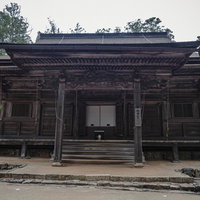 高野山の大会堂の正面外観、黒い柱と装飾的な軒下の大規模木造建築の写真