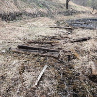 廃工場跡地に散乱する朽ちた木材と水溜りのある荒地の写真