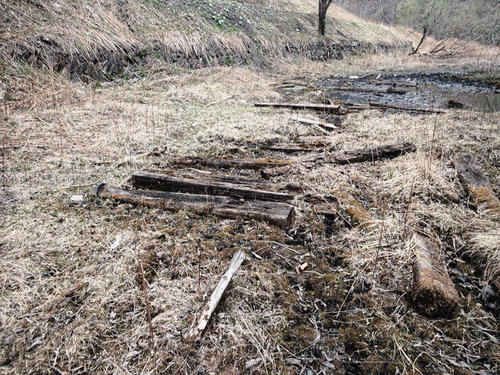 廃工場跡地に散乱する朽ちた木材と水溜りのある荒地