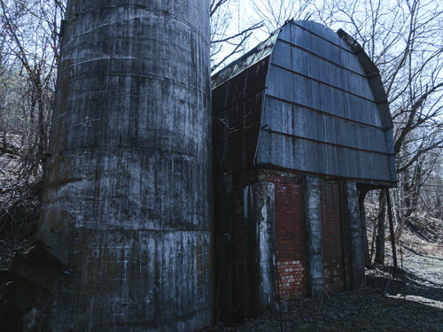 錆びついた円筒形サイロと煉瓦造りの廃工場建屋