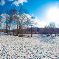 青空に輝く太陽と真っ白な雪原の冬景色の写真
