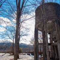 廃工場のホッパーと残雪の河川風景 冬の工業遺産の写真