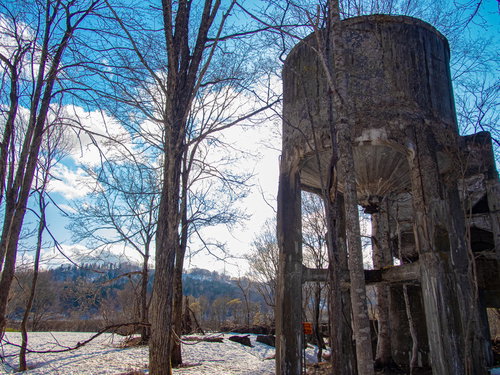 廃工場のホッパーと残雪の河川風景 冬の工業遺産