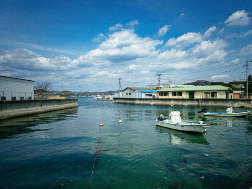 青空と白い雲が広がる尾道の百島の港と停泊する小型漁船