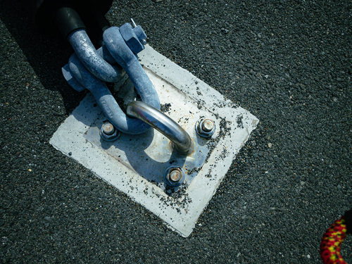 コンクリート台座に固定された青いチェーンと金属杭