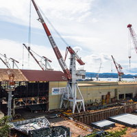 呉市の造船所で稼働する大型クレーン群と建造中船舶の写真