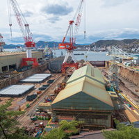 呉市造船所の赤いクレーン群と建造中船舶の空撮風景の写真