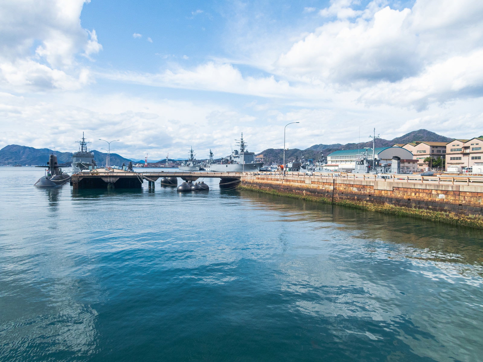 青い海面に停泊する潜水艦と背景の山々が映る風景