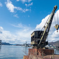 呉の港に停泊する軍艦とクレーン、海上自衛隊の船着場の写真