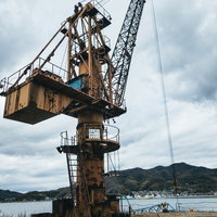 河畔に立つ錆び付いた造船クレーンの写真