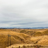 曇天の大観峰と枯れ草の丘陵の写真