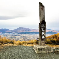 大観峰の標柱と阿蘇の山並みの写真