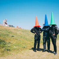 正義活動をする匿名のカラーコーン3人が河川敷で手を組むポーズの写真