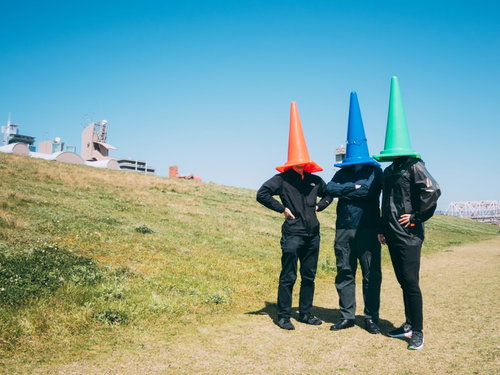 正義活動をする匿名のカラーコーン3人が河川敷で手を組むポーズ