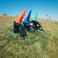 河川敷で語り合う赤・青・緑のカラーコーン三兄弟の写真