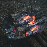 焚き火台で燃える木材と赤々とした炎の夜間風景の写真