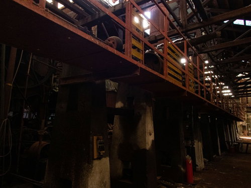 薄明りに照らされた製紙工場の廃工場内部の機械設備