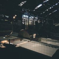 製紙工場の廃墟に残る錆びたタイル壁と金属梁の写真