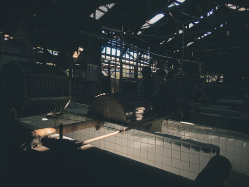 製紙工場の廃墟に残る錆びたタイル壁と金属梁