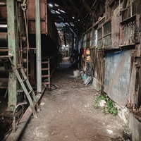閉鎖した製紙工場の薄暗い通路と錆びた配管設備の写真