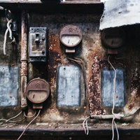 ボロボロに錆び付いた古いブレーカーや計器の写真