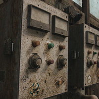 埃にまみれた廃工場の計器スイッチと配電盤の写真