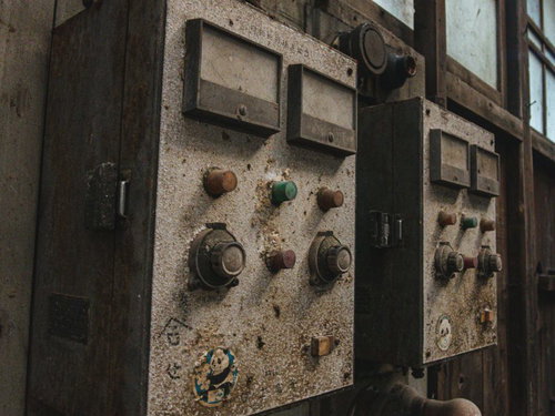 埃にまみれた廃工場の計器スイッチと配電盤