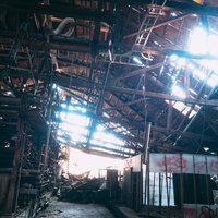 廃工場で崩れ落ちた天井から差し込む光と錆びた骨組みの写真