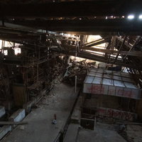 天井が崩れ落ちた倒壊した製紙工場の廃墟と散乱する機械設備の写真