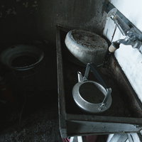 廃病院の錆びた不気味な流し台に置かれた古いやかんと散乱物の写真