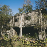緑に囲まれたボロボロになった炭鉱の建造物跡の写真