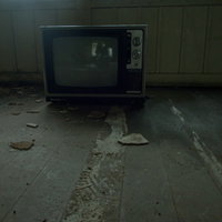 廃屋の薄暗い室内にぽつんと置かれた古いカラーテレビの写真