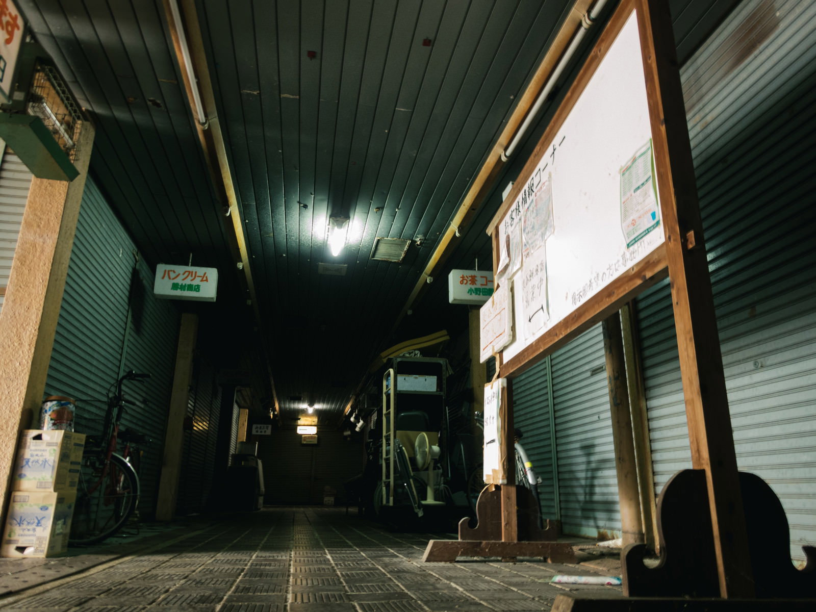 薄暗いアーケード内でシャッターが下りた店舗が並ぶ商店街