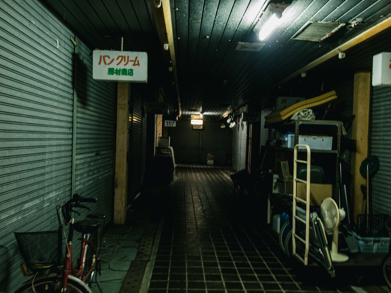 シャッターが全て閉まった薄暗い商店街のアーケード内