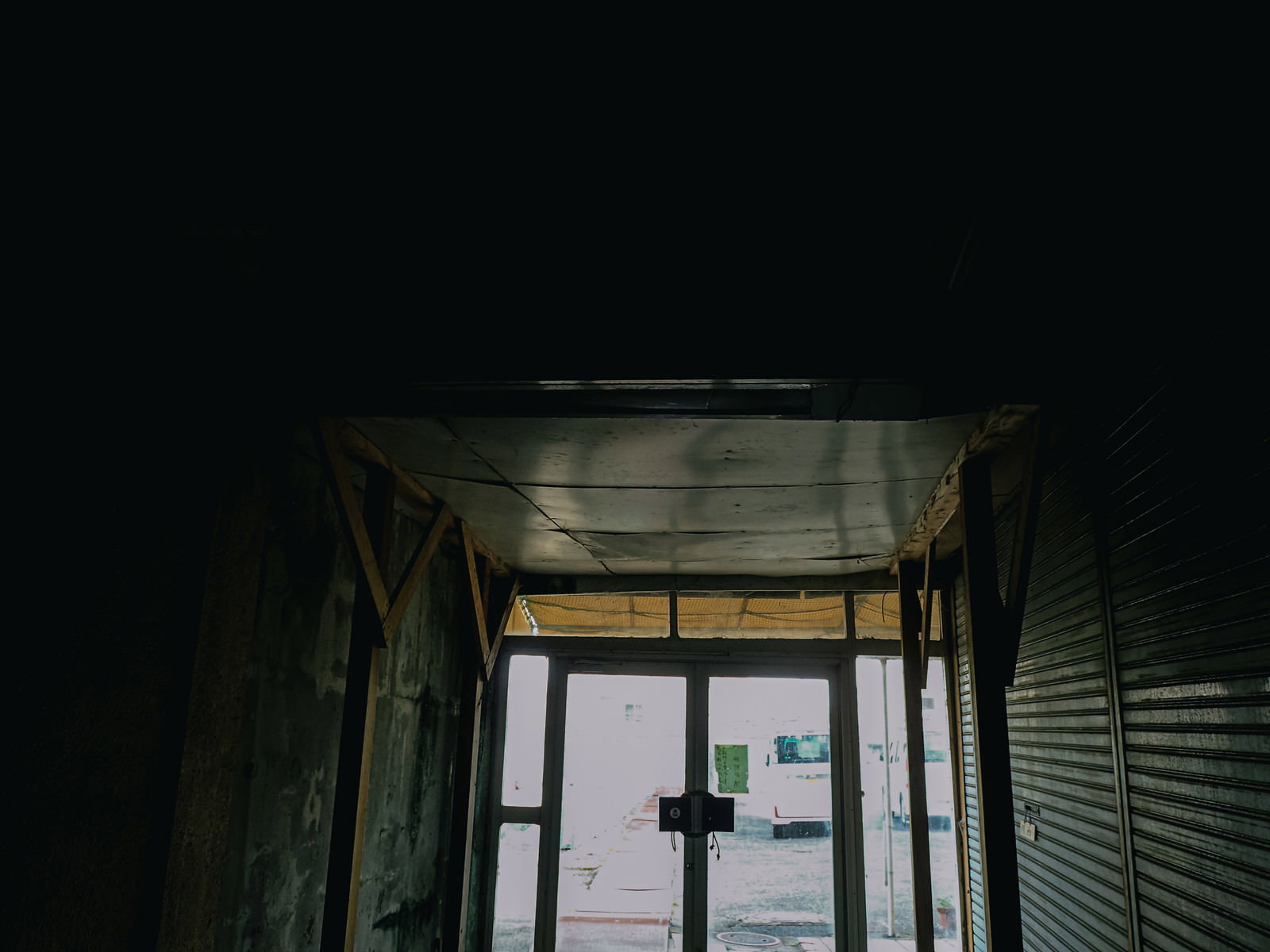 薄暗いアーケード内から外の光が差し込む廃墟のような市場の出口