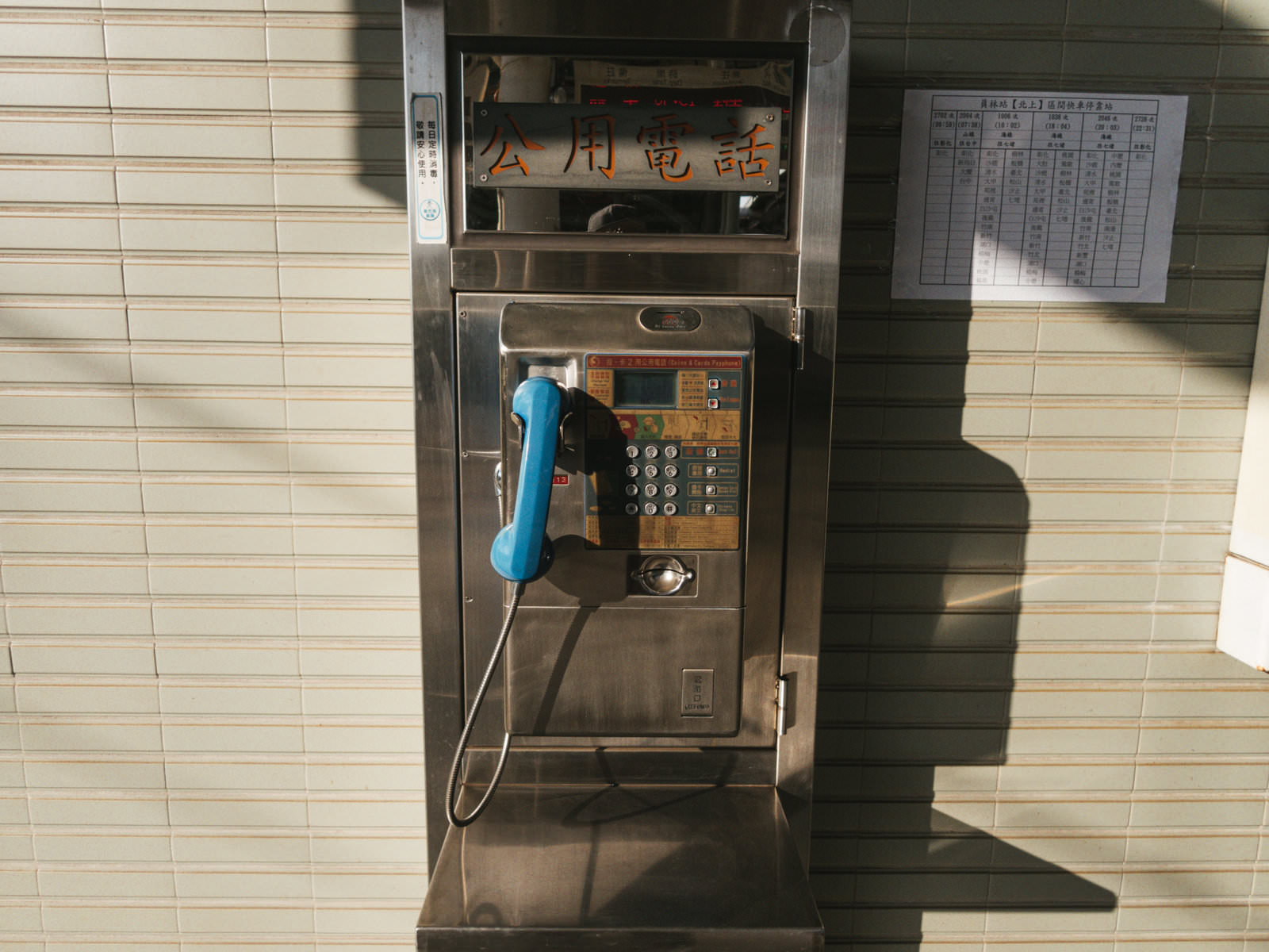 台湾の駅に設置された青い受話器がついた古いステンレス製の公衆電話ボックス